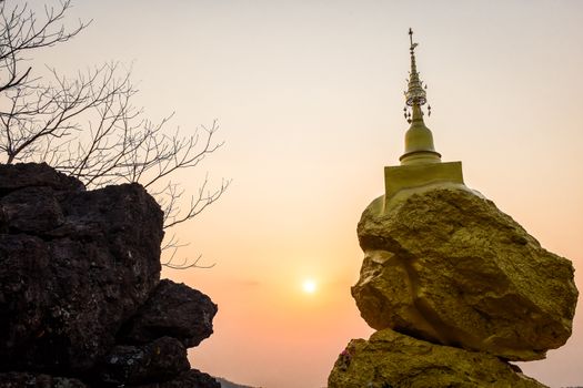 golden pagoda on golden rock stone on mountain with sunset in background