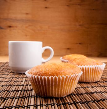 espresso coffee in a white china cup and cupcake over wooden mat