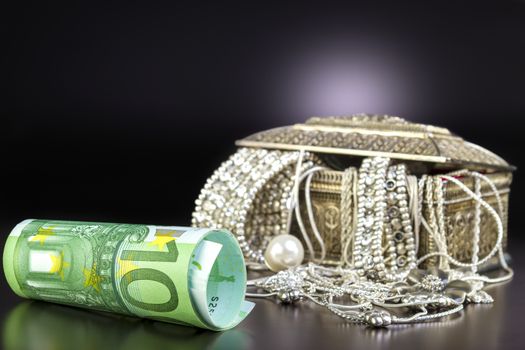 Silver jewelry and Euro on black background. Focus on money