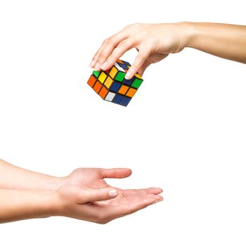 Hand dropping color cube on white background
