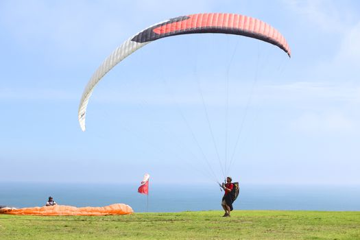 LIMA, PERU - FEBRUARY 20, 2012: Unidentified person with a paraglider on the coast of Miraflores on February 20, 2012 in Lima, Peru. Paragliding is a popular sport on the coast of Miraflores, where winds are usually good and in good weather a big part of the coast of Lima can be seen. 