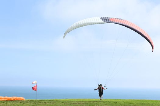 LIMA, PERU - FEBRUARY 20, 2012: Unidentified person taking off with a paraglider on the coast of Miraflores on February 20, 2012 in Lima, Peru. Paragliding is a popular sport on the coast of Miraflores, where winds are usually good and in good weather a big part of the coast of Lima can be seen. 