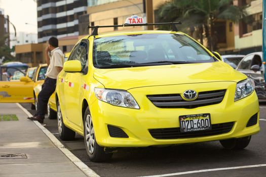 LIMA, PERU - MARCH 16, 2012: Yellow taxi standing on the Malecon de la Reserva at Larcomar waiting for passengers on March 16, 2012 in Miraflores, Lima, Peru. There are many taxis in Lima, and they are used very frequently by the people. 