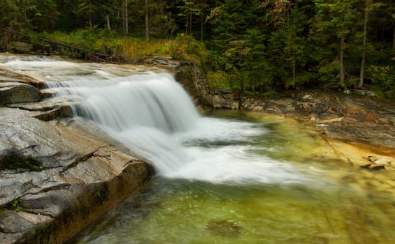 Large waterfall between forest and mossy rock