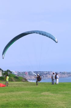 LIMA, PERU - MARCH 19, 2012: Unidentified person with a paraglider on the coast of Miraflores with a view of the coast of Miraflores and Barranco in the back on March 19, 2012 in Lima, Peru. Paragliding is a popular sport on the coast of Miraflores, where winds are usually good and in good weather a big part of the coast of Lima can be seen. 