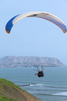 LIMA, PERU - MARCH 19, 2012: Unidentified people in paragliding tandem flight at the coast of Miraflores with view onto Chorrillos in the back on March 19, 2012 in Lima, Peru. Paragliding is a popular sport on the coast of Miraflores, where winds are usually good and in good weather a big part of the coast of Lima can be seen. 