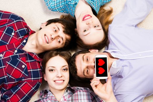 four young people are together, the young man pressed his lips to the phone