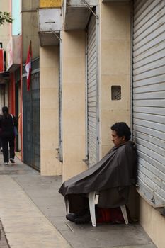 LIMA, PERU - JULY 21, 2013: Unidentified person sitting in front of a closed shop on July 21, 2013 in Miraflores, Lima, Peru.