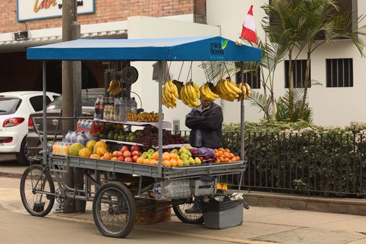 LIMA, PERU - JULY 23, 2013: Unidentified street vendor selling fruits from a cart on the street on July 23, 2013 in Miraflores, Lima, Peru. Mobile food and fruit carts and stands are a very common sight all over Lima. 