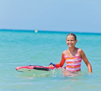 Summer vacation - Happy cute girl having fun with surfboard in the ocean