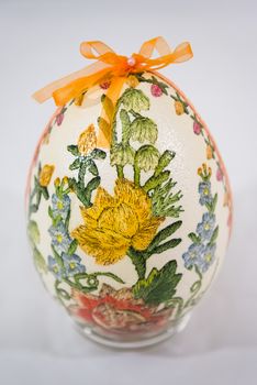 Easter egg decorated with flowers made by decoupage technique on light background