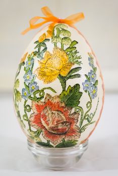 Easter egg decorated with flowers made by decoupage technique on light background