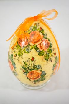 Easter egg decorated with flowers made by decoupage technique on light background