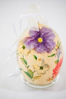 Easter egg decorated with flowers made by decoupage technique on light background