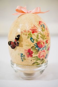 Easter egg decorated with flowers made by decoupage technique on light background