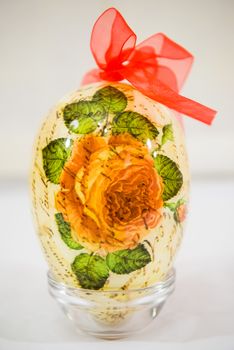 Easter egg decorated with flowers made by decoupage technique on light background