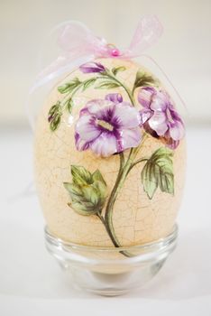 Easter egg decorated with flowers made by decoupage technique on light background