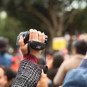 LIMA, PERU - JULY 21, 2013: Unidentified person holding a video camera to film the Wong Parade in Miraflores on July 21, 2013 in Lima, Peru. The Parade (Gran Corso de Wong) is a traditional parade to celebrate the Peruvian national holiday which is on July 28-29. 