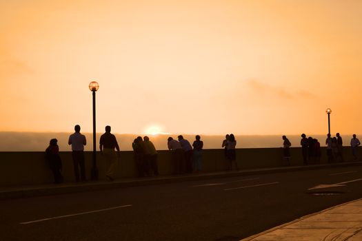 LIMA, PERU - MARCH 11, 2012: Unidentified people watching the sunset over the Pacific ocean from the pavement along the Malecon de la Reserva in Miraflores on March 11, 2012 in Lima, Peru. 