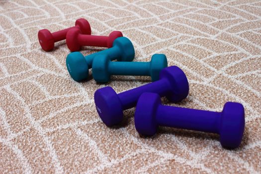 Colorful dumbbells lie asymmetrically ready for sports