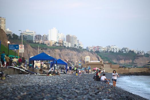 LIMA, PERU - APRIL 2, 2012: Unidentified people on the rocky Pacific coast of Miraflores on April 2, 2012 in Lima, Peru. On the top of the steep coast the modern residential buildings of Miraflores can be seen. 