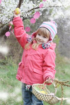 Pretty girl holding painted egg outdoor in spring