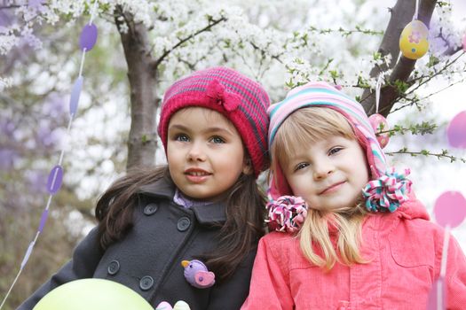 Pretty girls together holding painted egg outdoor in spring