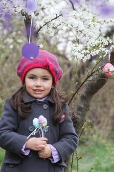 Pretty girl holding painted egg outdoor in spring