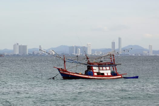 fishing boat in the sea with city view background
