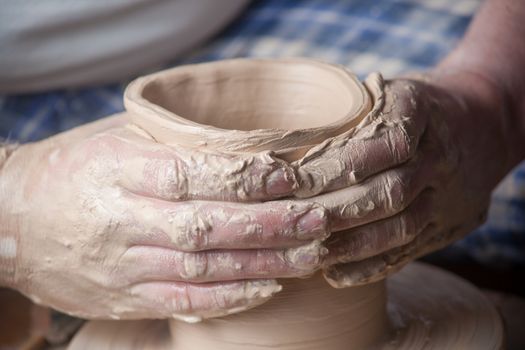 Hands of a potter, creating an earthen jar on the circle