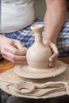 Hands of a potter, creating an earthen jar on the circle