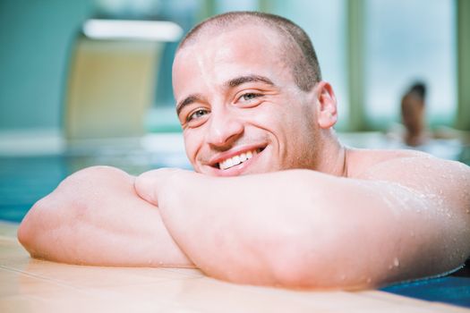 Young attractive male posing with a smile in a swimming pool