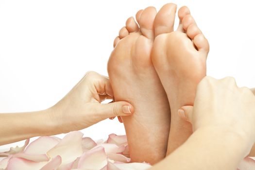 woman foot receiving gentle massage on bed with rose petals, isolated with work path