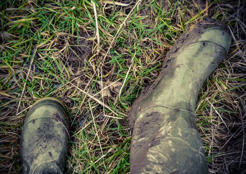 Retro Faded Photo Of Dirty Rubber Boots In The Countryside
