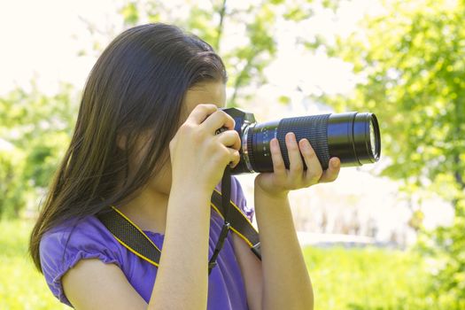 Portrait of brunette girl, taking photos at summer green park.