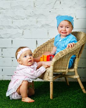 Brother and sister playing in the backyard next to the wicker chair