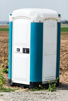 Blue portable mobile toilet next to a construction site