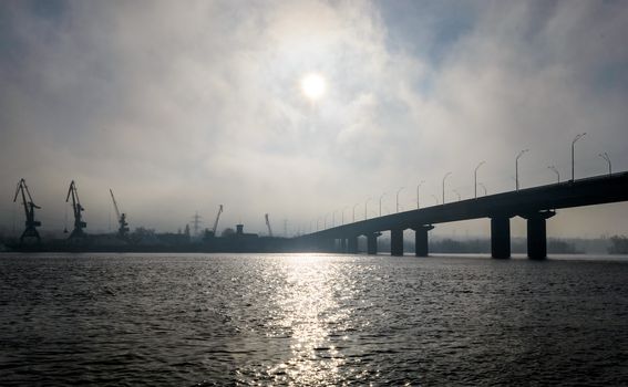 Bridge over a wide river in a fog