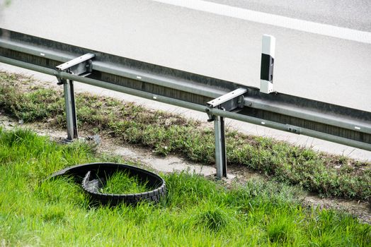 Broken truck tyre being left on the shoulder of a highway in the green grass