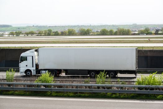 White truck moving on a highway nest to airport runway with space for your company logo and text