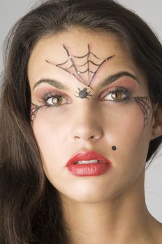 close up of young and nice brunette with spider web painted on face