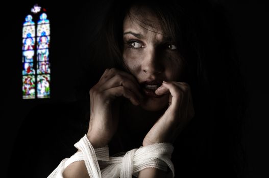 woman in fear with patch around her arms an a church windows on back