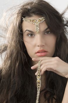 cute brunette with golden jewel and hair in wind