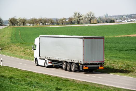 White truck moving on a main road with space for your company logo and text