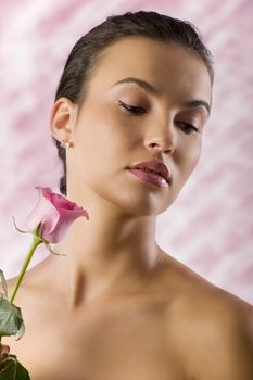 close up portrait of a pretty brunette with a pink rose looking down