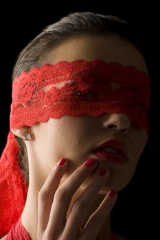 close up portrait of a young brunette on black background with a red mask of lace