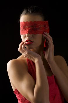 sensual portrait of a young brunette on black background with a red mask of lace