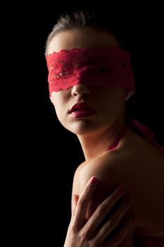 sensual portrait of a young brunette on black background with a red mask of lace