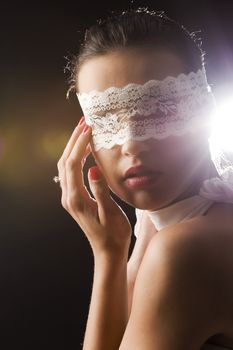 cute young woman with dark hair white lace mask in a portrait with strong backlight