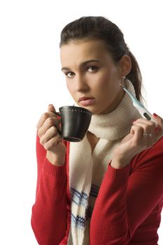 nice brunette with a thermometer fighting against a cold with a cup of hot drink